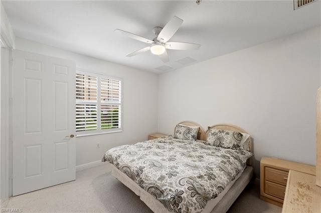 3142 Aviamar Cir, #2104, Naples, FL 34114 White paneled interior door, window with plantation shutters, ceiling fan with integrated lighting, and neutral carpeting