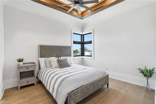 280 Estrellita Dr, Fort Myers Beach, FL 33931 Bedroom with light wood-style floors, ornamental molding, a ceiling fan, and a raised ceiling - Virtually Edited Image