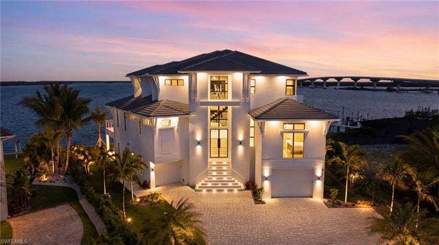 280 Estrellita Dr, Fort Myers Beach, FL 33931 Modern home featuring an attached garage, a tile roof, driveway, and stucco siding - Virtually Edited Image