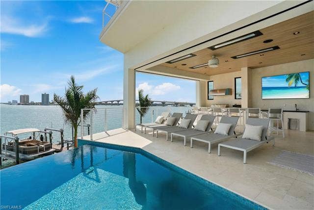 280 Estrellita Dr, Fort Myers Beach, FL 33931 View of swimming pool with an infinity pool, exterior bar, grilling area, and a water view - Virtually Edited Image
