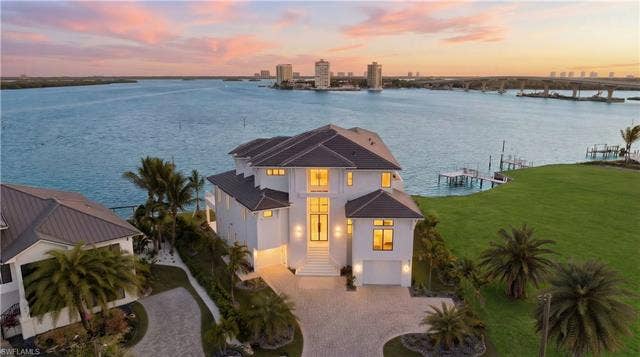 280 Estrellita Dr, Fort Myers Beach, FL 33931 View of front of house featuring a water view, decorative driveway, stucco siding, a view of city, and an attached garage - Virtually Edited Image