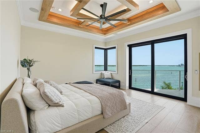 280 Estrellita Dr, Fort Myers Beach, FL 33931 Bedroom featuring a water view, access to exterior, light wood-style floors, a ceiling fan, and ornamental molding - Virtually Edited Image