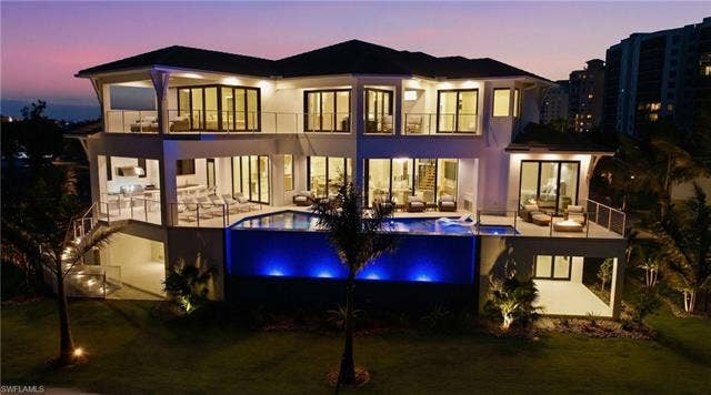 280 Estrellita Dr, Fort Myers Beach, FL 33931 Rear view of house with an infinity pool, a balcony, a yard, and an outdoor lounge area - Virtually Edited Image