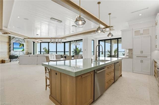 280 Estrellita Dr, Fort Myers Beach, FL 33931 Kitchen with two tone color scheme, open floor plan, a large island with sink, light stone countertops, and pendant lighting - Virtually Edited Image