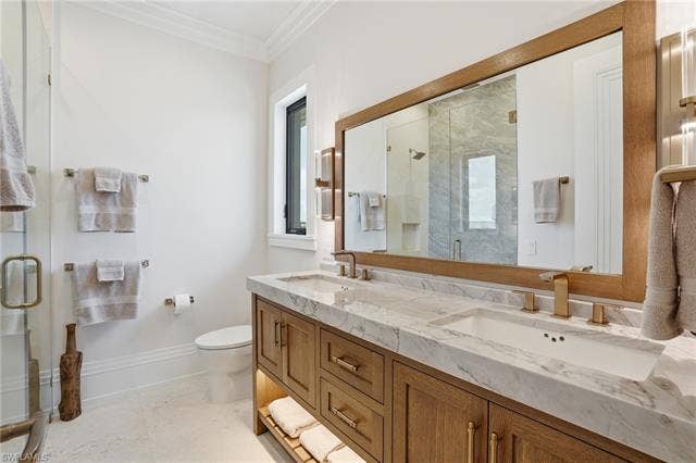 280 Estrellita Dr, Fort Myers Beach, FL 33931 Bathroom featuring a shower stall, crown molding, and double vanity - Virtually Edited Image