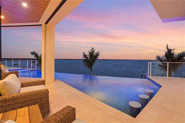 280 Estrellita Dr, Fort Myers Beach, FL 33931 Pool at dusk featuring an outdoor pool and a water view - Virtually Edited Image