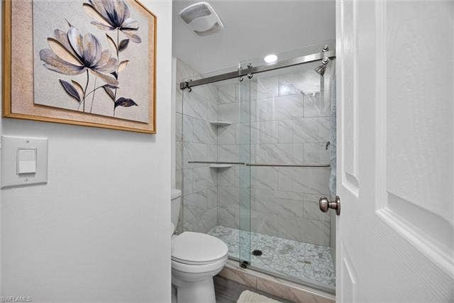 6220 Augusta Dr, #117, Fort Myers, FL 33907 Shower with sliding glass doors, white tiled walls, and a mosaic tiled floor