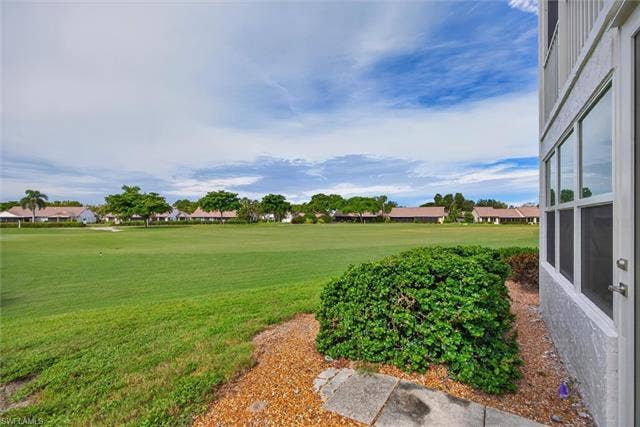 6220 Augusta Dr, #117, Fort Myers, FL 33907 Expansive green space with distant residential structures, mature trees, and a clear sky