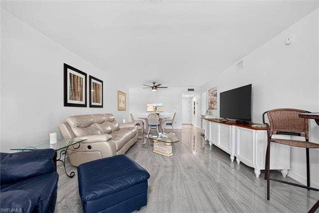 6220 Augusta Dr, #117, Fort Myers, FL 33907 Spacious living area featuring polished tile flooring, a built-in media console, and a dining area with ceiling fan