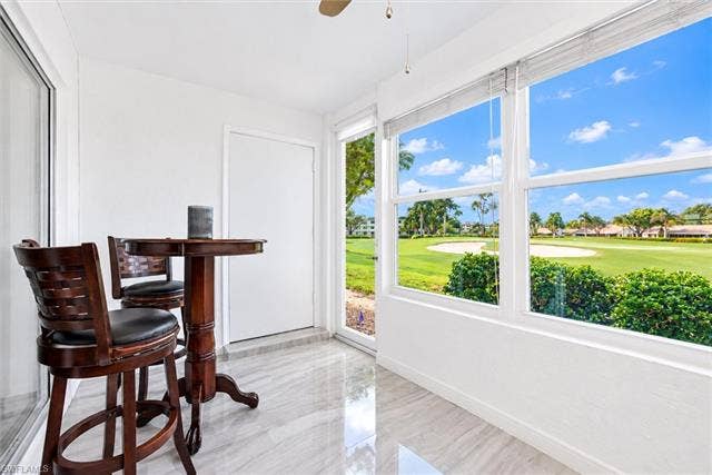 6220 Augusta Dr, #117, Fort Myers, FL 33907 Sunroom featuring large windows, golf course scenery, and polished tile flooring