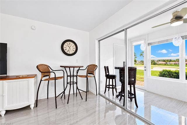 6220 Augusta Dr, #117, Fort Myers, FL 33907 White walls, light-toned tile flooring, and sliding glass doors with an outdoor ceiling fan