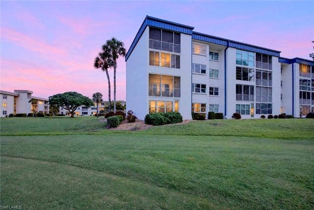 6220 Augusta Dr, #117, Fort Myers, FL 33907 Multi-story building with screened balconies, white exterior, and blue accents