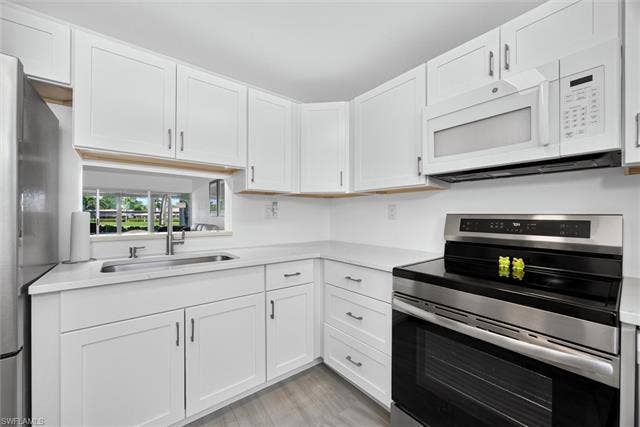 6220 Augusta Dr, #117, Fort Myers, FL 33907 White shaker-style cabinetry with chrome hardware, stainless steel sink, and light-toned countertops