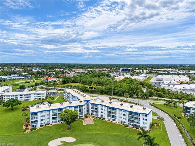 6220 Augusta Dr, #117, Fort Myers, FL 33907 Elevated aerial perspective showcasing multiple residential buildings, lush green landscaping, and surrounding urban development