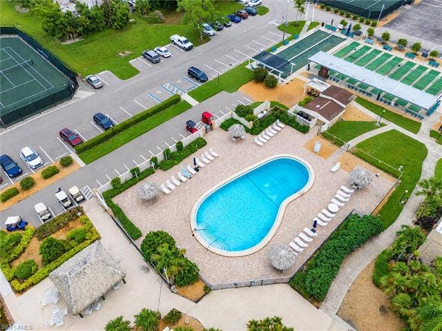 6220 Augusta Dr, #117, Fort Myers, FL 33907 Resort-style pool area with ample lounge seating, a surrounding paver deck, and lush landscaping