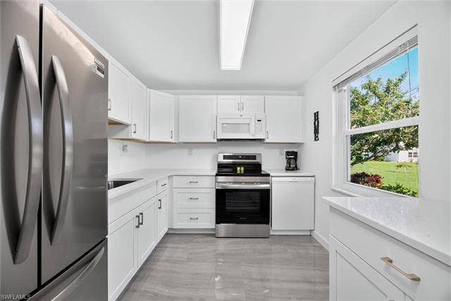6220 Augusta Dr, #117, Fort Myers, FL 33907 White cabinetry with matte hardware, stainless steel appliances, light-toned countertops, and grey tile flooring