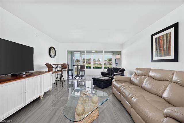 6220 Augusta Dr, #117, Fort Myers, FL 33907 Bright living area featuring tile flooring, a built-in media console, and an additional dining area