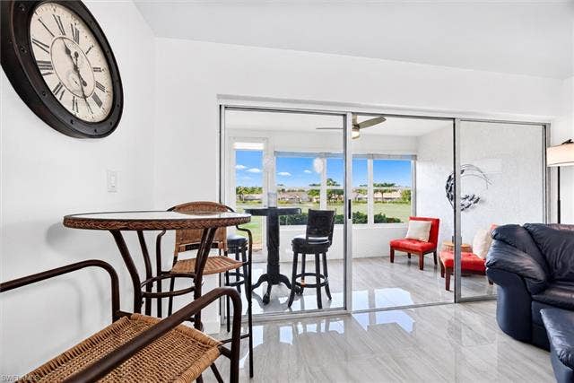 6220 Augusta Dr, #117, Fort Myers, FL 33907 Sliding glass doors opening to an enclosed patio with tile flooring and a ceiling fan