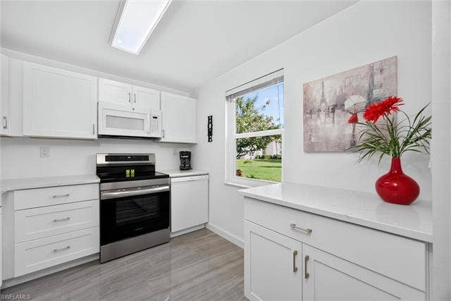 6220 Augusta Dr, #117, Fort Myers, FL 33907 Contemporary kitchen featuring white shaker cabinetry, stainless steel appliances, light-toned countertops, a rectangular ceiling light fixture, and tile flooring