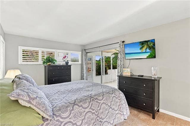 2816 18th Ave, Cape Coral, FL 33904 Sliding glass doors leading to an exterior space, multiple windows with white plantation shutters, and light-toned tile flooring