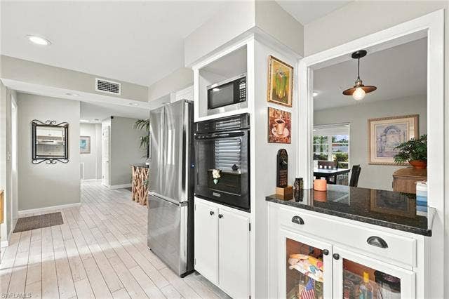 2816 18th Ave, Cape Coral, FL 33904 Kitchen featuring a stainless steel refrigerator, built-in wall oven and microwave, white cabinetry with dark hardware, and dark countertop