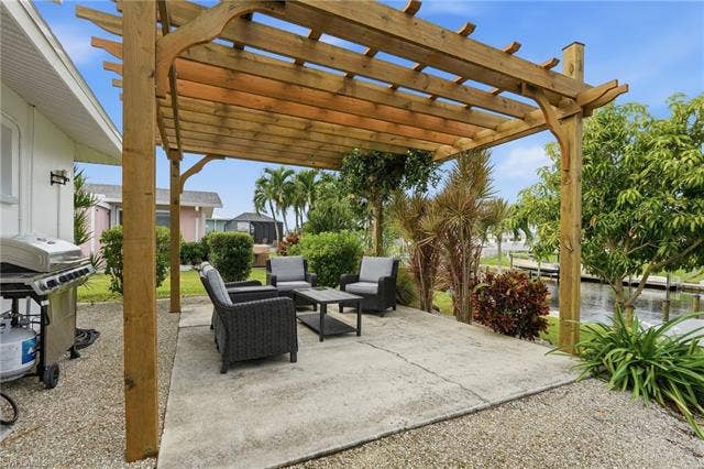 2816 18th Ave, Cape Coral, FL 33904 Expansive concrete patio with a wooden pergola, and lush landscaping