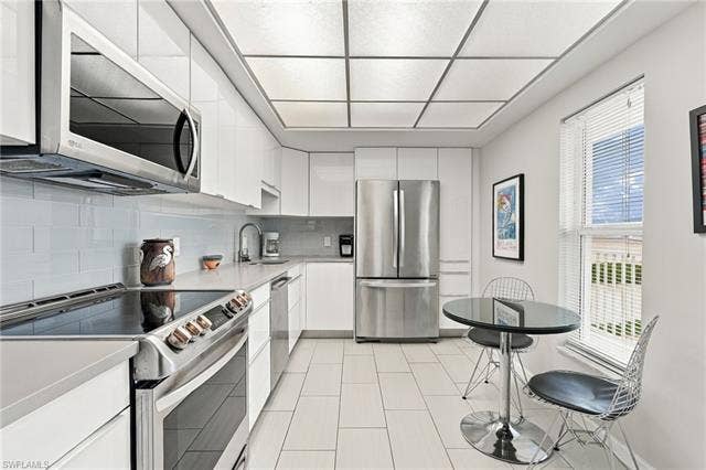 7000 Estero Blvd, #704, Fort Myers Beach, FL 33931 The bright kitchen features white cabinetry, solid-surface Corian countertops and stainless steel appliances. - Virtually Edited Image