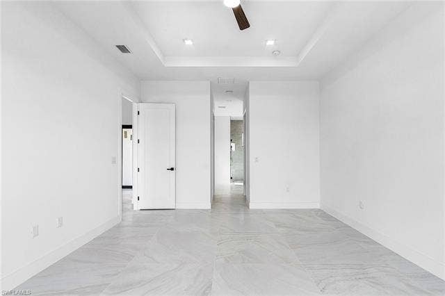4116 36th Ln, Cape Coral, FL 33993 Spacious interior featuring large format tile flooring, a tray ceiling, recessed lighting, and a ceiling fan