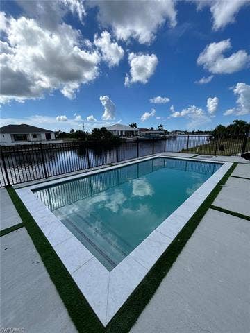 4116 36th Ln, Cape Coral, FL 33993 Rectangular pool featuring a tiled edge, artificial turf accents, and concrete decking