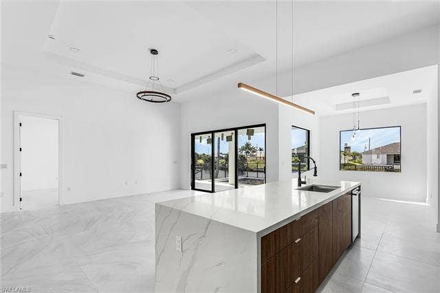 4116 36th Ln, Cape Coral, FL 33993 Expansive white tile flooring throughout, featuring a central kitchen island with a waterfall countertop and wood-finish cabinetry