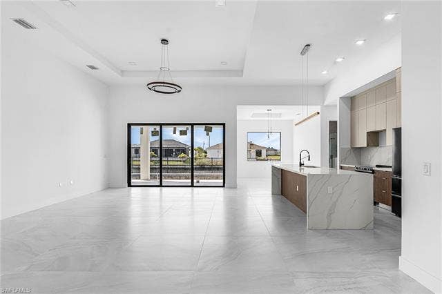 4116 36th Ln, Cape Coral, FL 33993 Spacious interior with large format tile flooring, recessed lighting, a modern kitchen island with an integrated sink, and floor-to-ceiling sliding glass doors