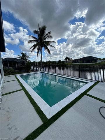 4116 36th Ln, Cape Coral, FL 33993 Rectangular swimming pool with a tile surround, concrete decking, and artificial turf accents