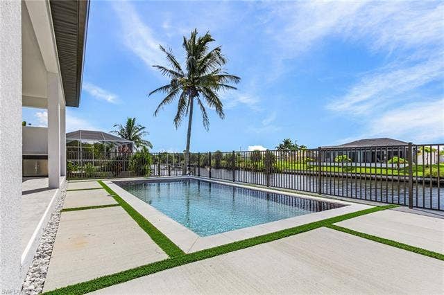 4116 36th Ln, Cape Coral, FL 33993 Rectangular in-ground pool with a surrounding concrete patio featuring artificial turf accents