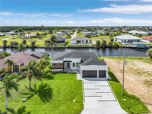 4116 36th Ln, Cape Coral, FL 33993 Modern exterior architecture with a dark shingle roof, integrated two-car garage, and a patterned concrete driveway