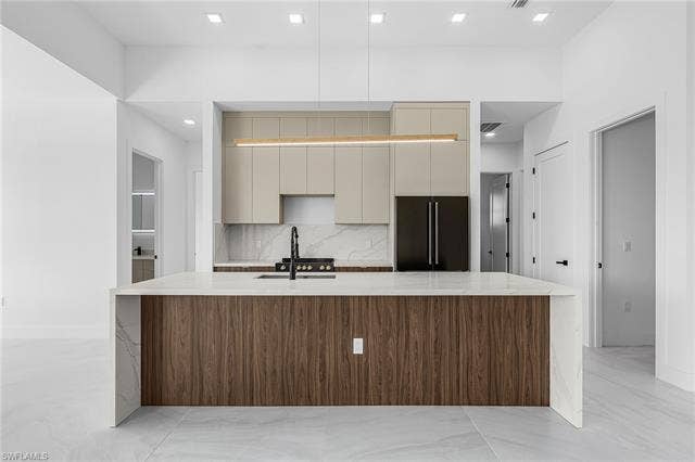 4116 36th Ln, Cape Coral, FL 33993 Waterfall island with wood-finish paneling, white countertops, integrated sink, and matte black faucet