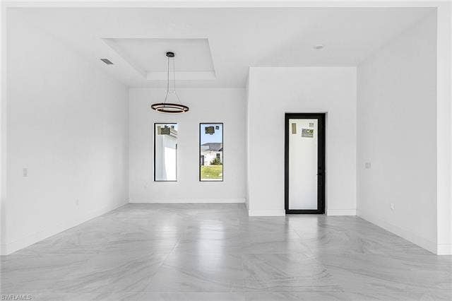 4116 36th Ln, Cape Coral, FL 33993 Recessed ceiling with a contemporary chandelier, two rectangular windows, gray-toned tile flooring, and a black-framed entry door