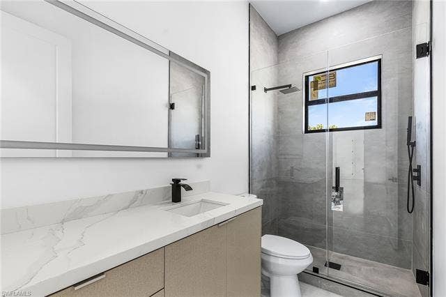 4116 36th Ln, Cape Coral, FL 33993 Sleek bathroom featuring a floating vanity with a light-toned countertop, a frameless glass shower enclosure, and matte black fixtures throughout