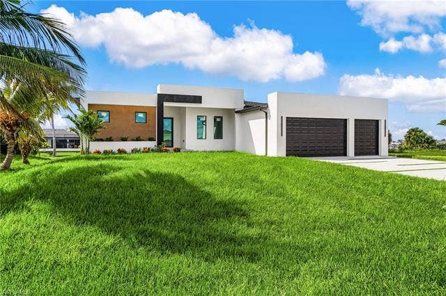 4116 36th Ln, Cape Coral, FL 33993 Modern architectural style with a flat roofline, integrated two-car garage, and a concrete driveway