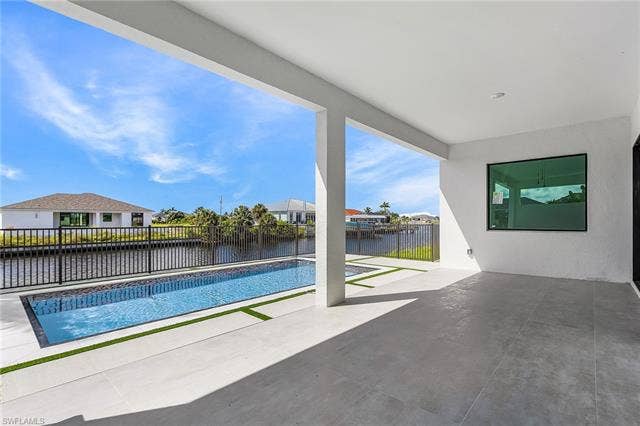 4116 36th Ln, Cape Coral, FL 33993 Covered patio with large format tile flooring, a rectangular pool, and water frontage with a black metal fence