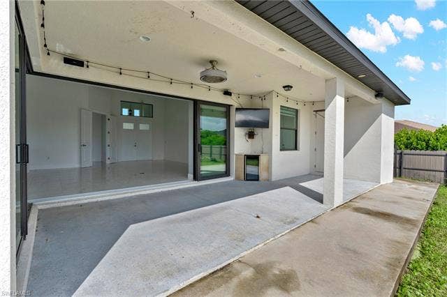 113 38 Pl, Cape Coral, FL 33993 Modern covered patio featuring polished concrete flooring, expansive glass sliding doors with aluminum framing, recessed ceiling lighting, and seamless access to the residence