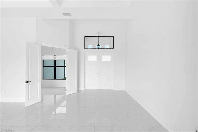 113 38 Pl, Cape Coral, FL 33993 High ceilings, white walls, and light-toned tile flooring create an expansive interior