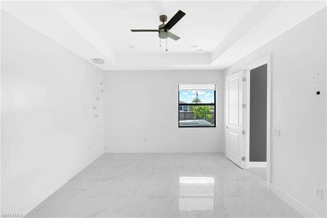 113 38 Pl, Cape Coral, FL 33993 Tray ceiling with recessed lighting, ceiling fan, contemporary pendant light fixture, white tile flooring, and white paneled doors