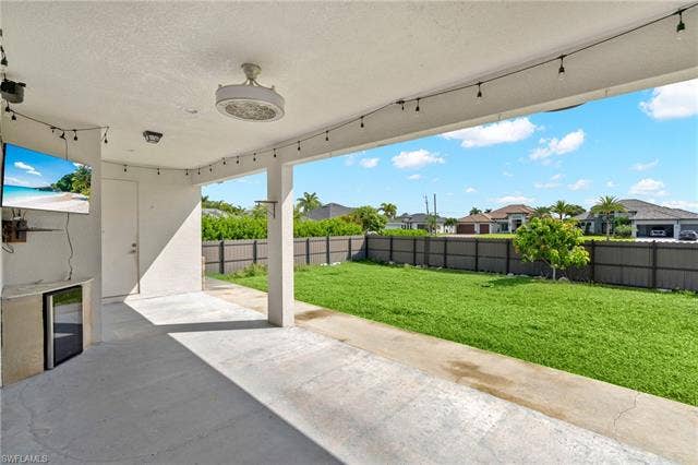 113 38 Pl, Cape Coral, FL 33993 Covered patio with a mounted outdoor television, built-in beverage cooler, ceiling fan, and concrete flooring