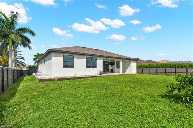 113 38 Pl, Cape Coral, FL 33993 Expansive backyard featuring a manicured lawn, established palm trees, and a privacy fence