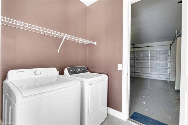 113 38 Pl, Cape Coral, FL 33993 Laundry area featuring a washer and dryer, wire shelving, and direct access to an attached garage with a finished floor