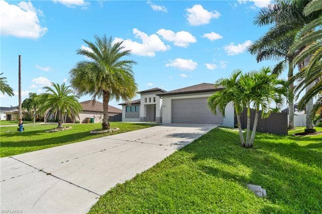113 38 Pl, Cape Coral, FL 33993 Contemporary architectural style with a two-car garage, concrete driveway, and mature palm trees