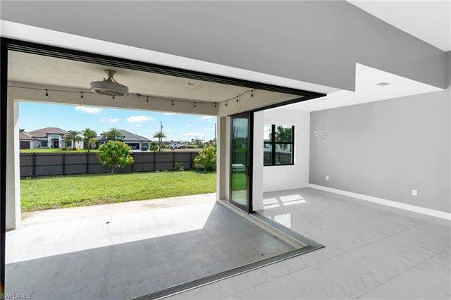 113 38 Pl, Cape Coral, FL 33993 Expansive tiled flooring extending into the outdoor patio, large glass sliding doors, recessed ceiling fan with integrated lighting, modern light fixture, and a spacious green lawn