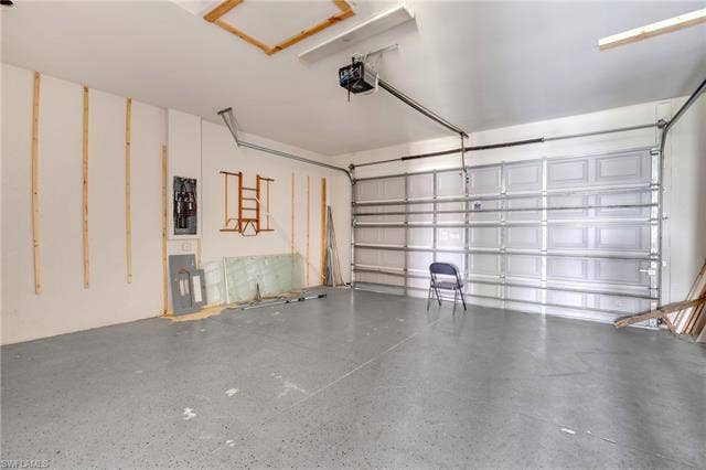 113 38 Pl, Cape Coral, FL 33993 Garage with concrete flooring, overhead garage door, and exposed ceiling joists