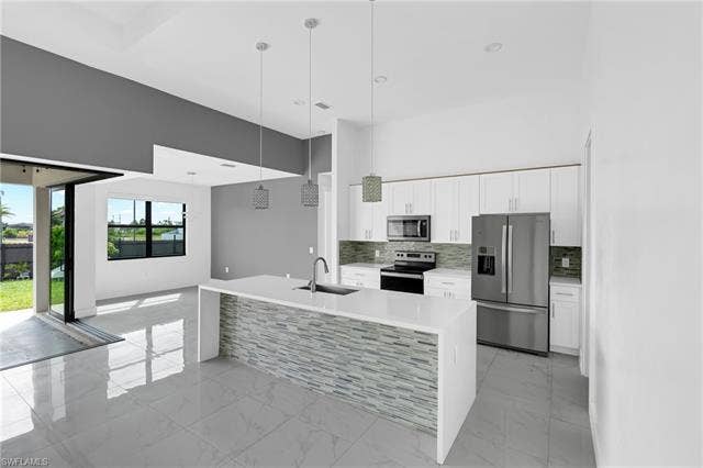 113 38 Pl, Cape Coral, FL 33993 Modern kitchen island with a waterfall countertop and stacked tile facade