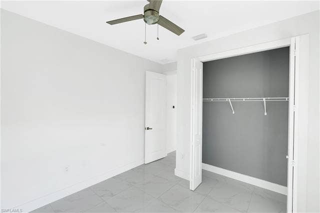 113 38 Pl, Cape Coral, FL 33993 Light gray tiled flooring, modern ceiling fan, white paneled door, and built-in closet shelving